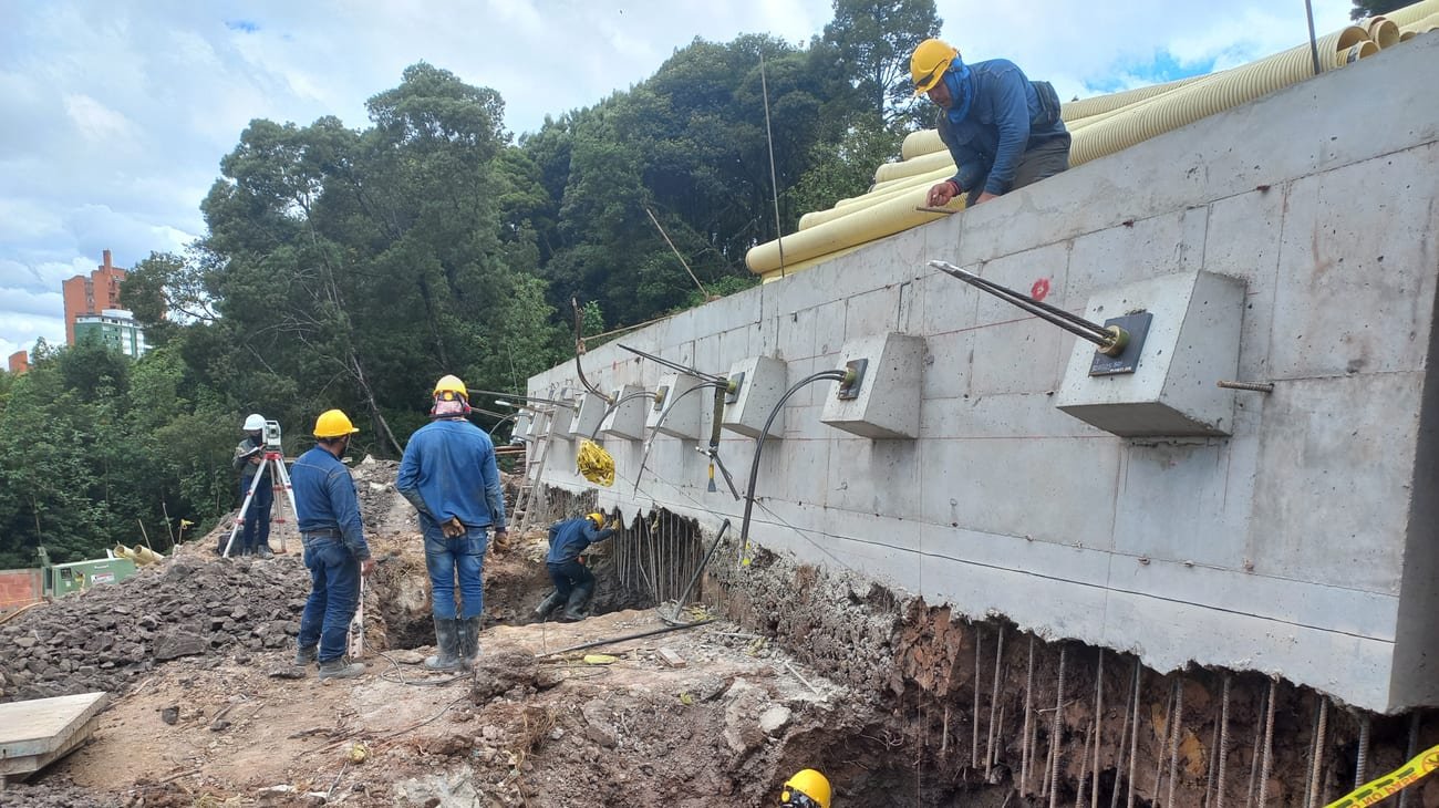 Muro anclado en ejecución con cuadrilla y equipo topógrafo, proyecto Policarpa